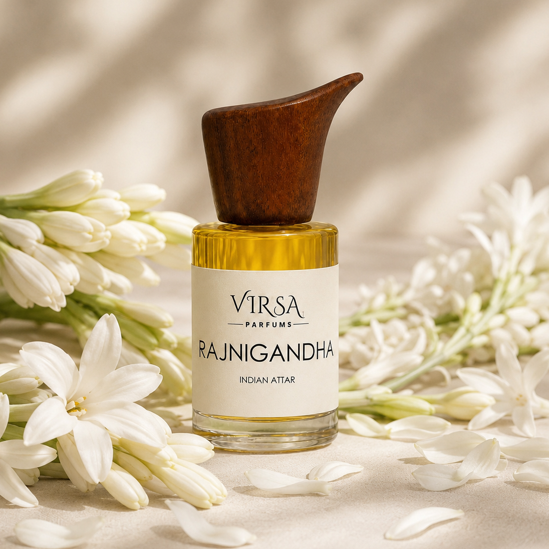 A bottle of VIRSA PARFUMES RAJNIGANDHA Indian Attar perfume with a dark brown wooden dropper cap, set on a beige surface surrounded by white flowers.